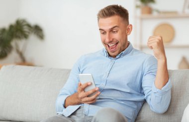 Heyecanlı erkek çalışan, elinde telefon tutmaktan çok mutlu.