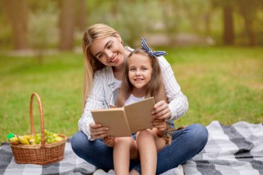 Genç Anne ve Kızı Kitap Okuyorlar Kırsalda piknik yapıyorlar