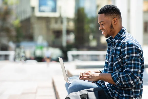 Homem negro feliz usando laptop, vista lateral — Fotografia de Stock