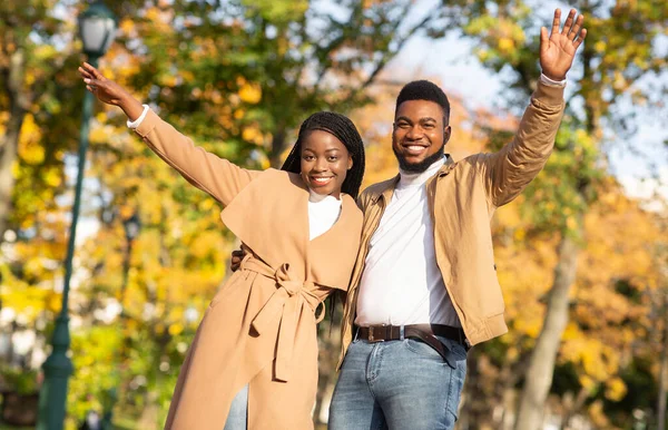在秋天的公园里，一对时髦的黑人夫妇高举双手摆姿势 — 图库照片