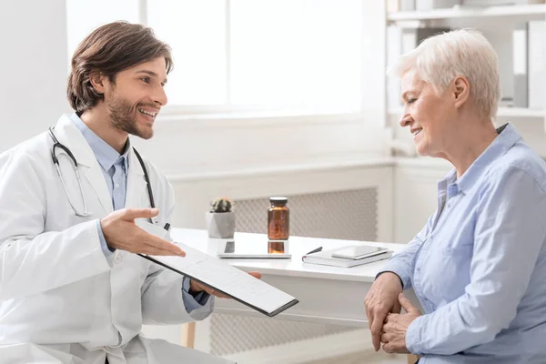 Alegre médico explicando plan de tratamiento a paciente mujer mayor — Foto de Stock