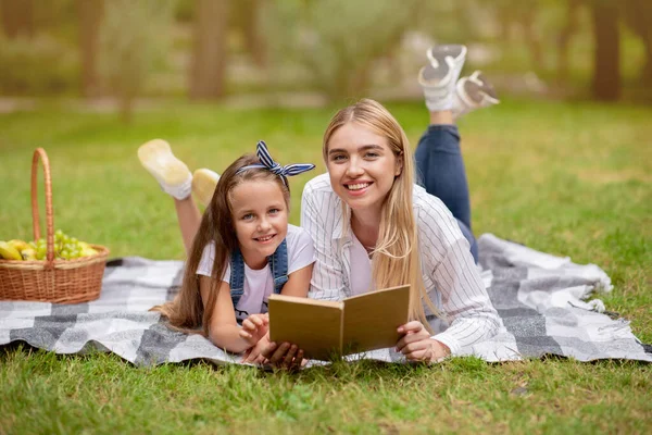 Boldog anya és kicsi lánya olvasás könyv miután piknik szabadban — Stock Fotó