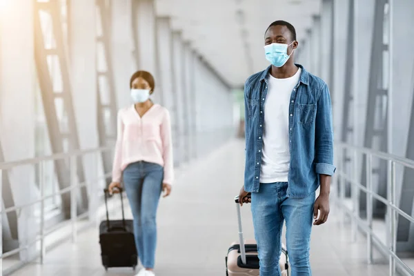 Gente africana feliz con máscaras médicas caminando con equipaje en la terminal del aeropuerto —  Fotos de Stock