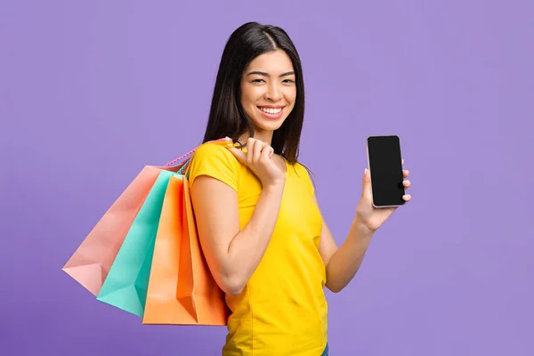 Shopping online. felice asiatico ragazza con shopper borse dimostrando nero smartphone schermo — Foto Stock