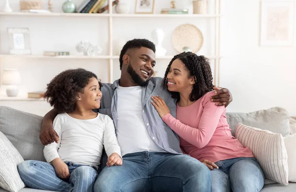 Family Home Lazer. felizes pais negros e pequena filha relaxante no sofá — Fotografia de Stock