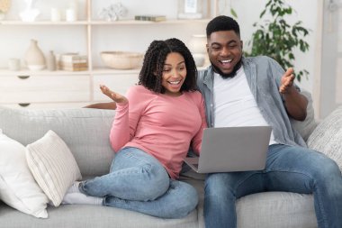 Harika bir internet teklifi. Mutlu siyah çift dizüstü bilgisayar kullanıyor ve heyecanla bağırıyor.