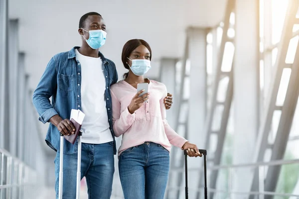 Coronavirus Travels. Pareja afroamericana que usa máscaras médicas protectoras en la terminal del aeropuerto —  Fotos de Stock
