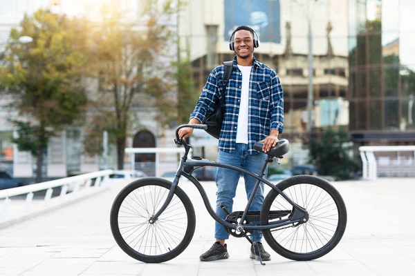 Retrato del tipo negro de pie con su bicicleta con auriculares — Foto de Stock