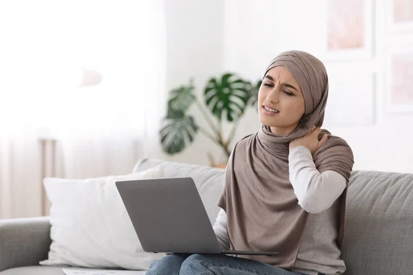 Dolore al collo. Donna musulmana che massaggia il collo infiammato stanco del lavoro sul computer portatile — Foto Stock
