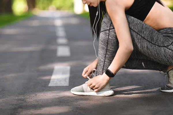 Koşmadan önce ayakkabı bağlayan, dışarıda koşuya hazırlanan sportif kız. — Stok fotoğraf