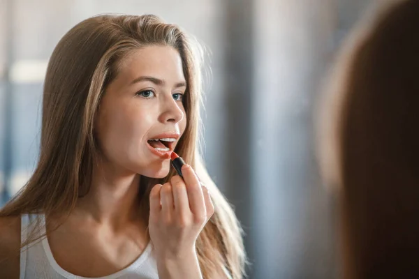 Attraktive junge Dame trägt Lippenstift auf ihren Lippen in der Nähe von Spiegel zu Hause, Leerstelle — Stockfoto