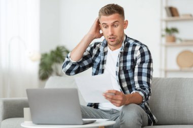 Düşünceli genç adam masada oturuyor, kağıda bakıyor.