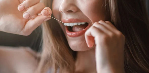 Menina jovem irreconhecível limpeza dos dentes com fio dental, close-up — Fotografia de Stock