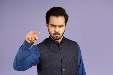 Öfkeli Hintli adam menekşe arkaplan üzerindeki suçlamalarla ekranı işaret ediyor.