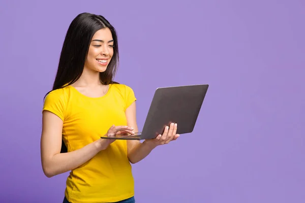 Edukacja online. Uśmiechnięta Azjatka za pomocą komputera Laptop na fioletowym tle — Zdjęcie stockowe