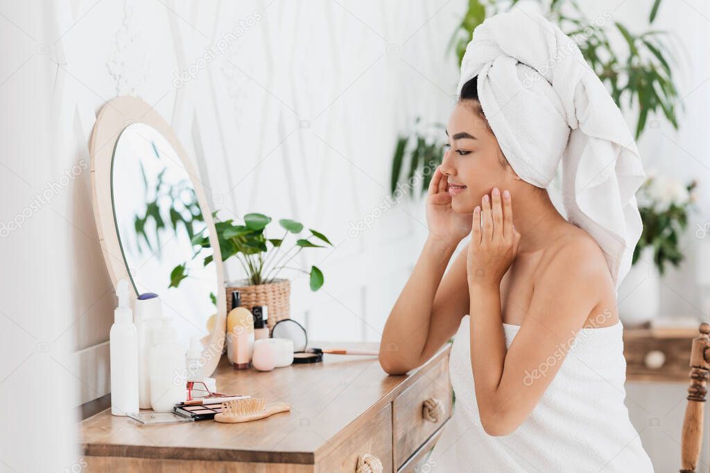 Side view of pretty asian girl putting make up