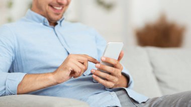 Evde akıllı telefon kullanan neşeli yetişkin adam.
