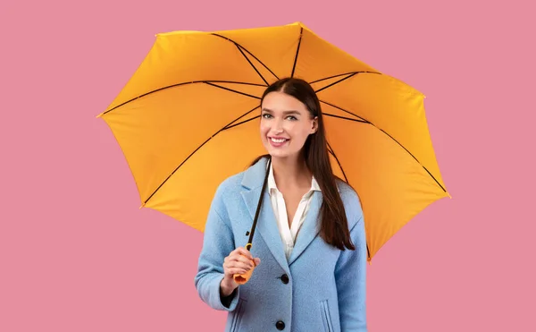 Portrait of cute girl holding umbrella at pink studio — Stock Photo, Image