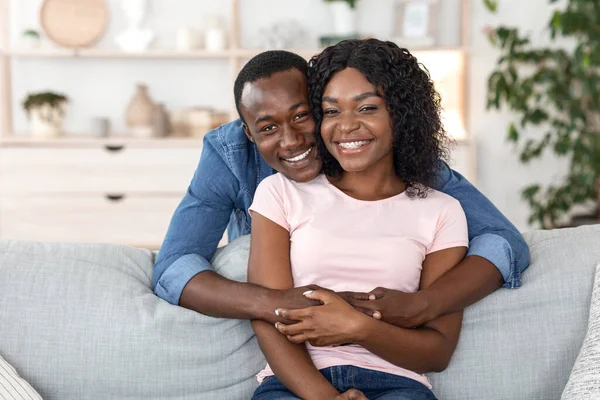 Красивая черная пара обнимается на диване дома — стоковое фото