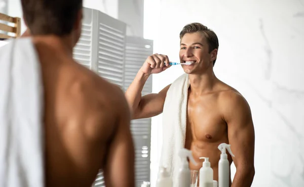 Snygg ung man med tandborste i badrummet — Stockfoto