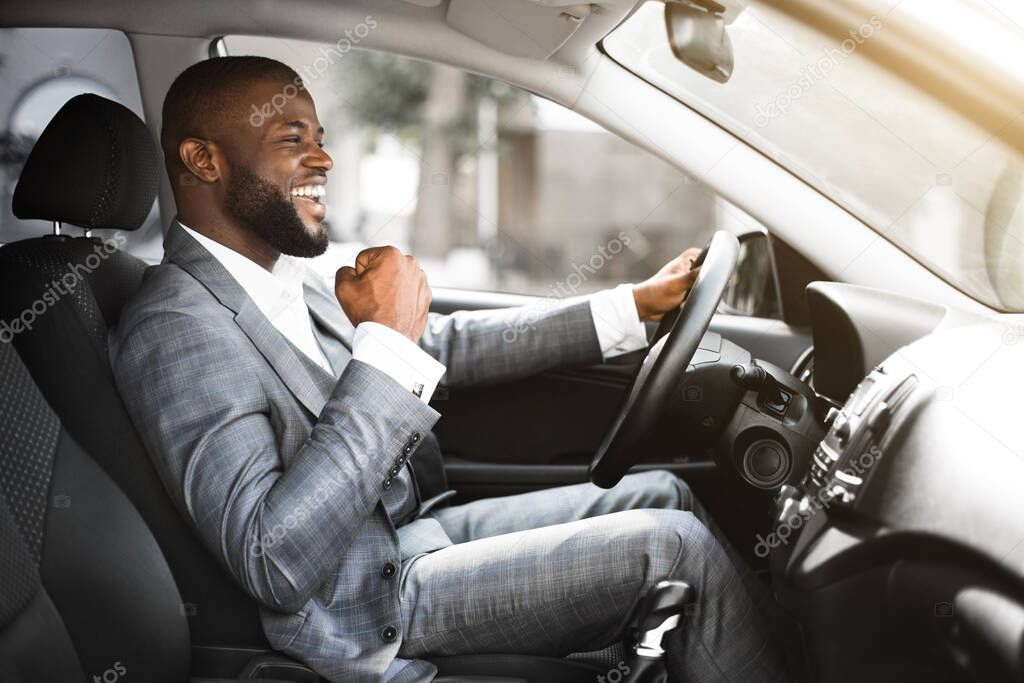 Young emotional black businessman driving after successful business meeting