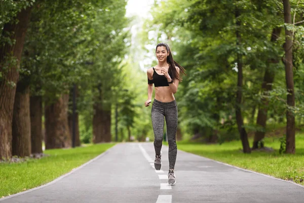 Stile di vita sportivo. Adatto donna asiatica che corre sul sentiero nel parco della città — Foto Stock