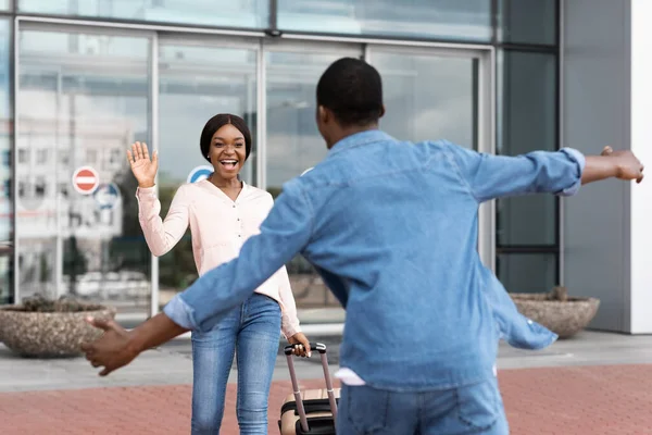 Счастливая африканская девушка встречает своего парня после приземления в аэропорту, машет рукой — стоковое фото