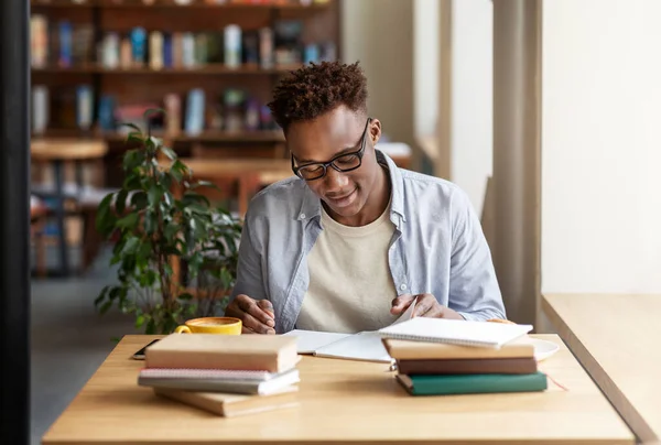 Heureux noir guy étudier ou travailler avec des livres à café — Photo