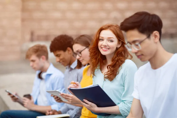 Linda chica estudiando al aire libre con sus amigos — Foto de Stock