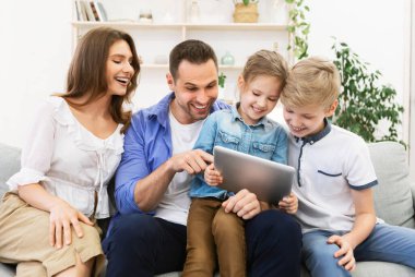 Aileler ve çocuklar tablet kullanıyor Evdeki koltukta oturuyorlar