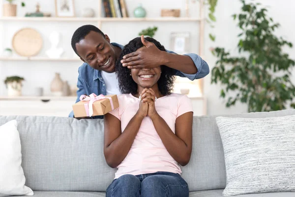 Africano con caja de regalo cubriendo sus ojos de mujer — Foto de Stock