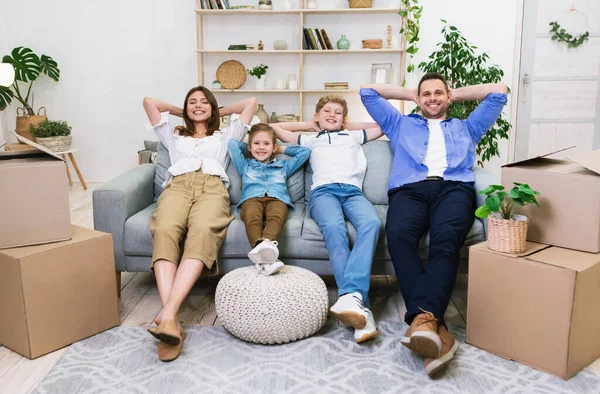 Gelukkig gezin ontspannen na het verplaatsen van nieuwe appartement zitten thuis — Stockfoto