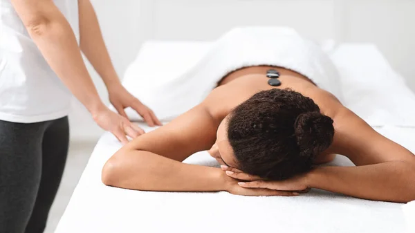 Afrikaans amerikaanse vrouw rusten tijdens hete steen massage in spa — Stockfoto