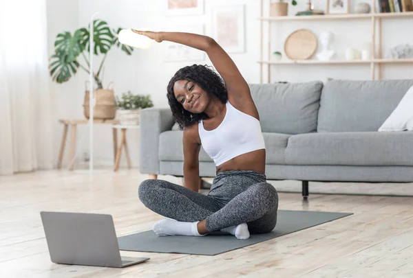 Sportliches schwarzes Mädchen übt zu Hause mit Laptop — Stockfoto