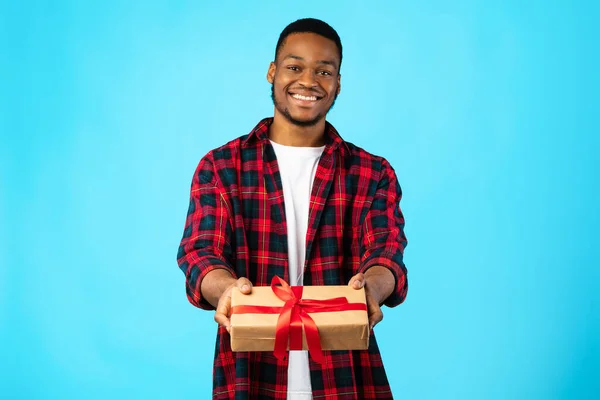 Cheerful African Guy Giving Gift To Camera Posing In Studio — Stock Photo, Image