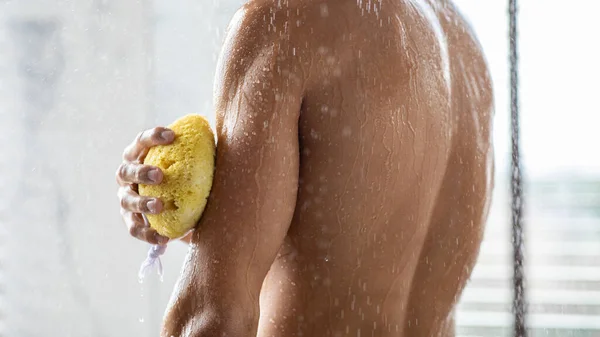 Schöner junger Mann wäscht sich die Arme mit Schwamm — Stockfoto