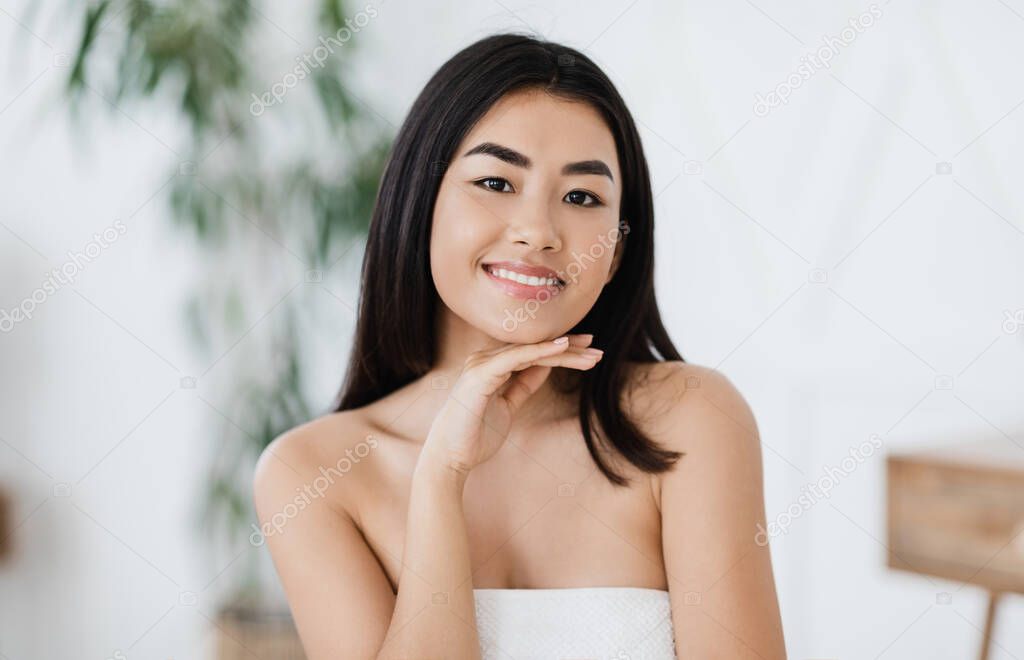 Young asian woman with perfect skin touching her chin
