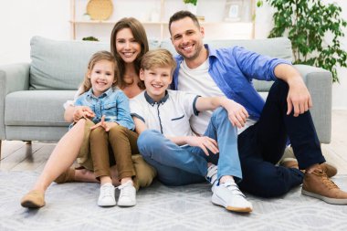 Evdeki kanepenin yanında oturan sevimli bir aile.