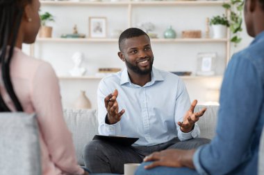 Confident black family counselor talking with married couple, giving advice to spouses clipart