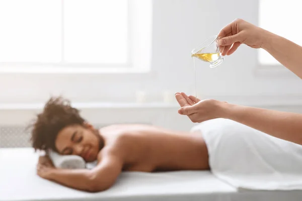 Massage therapist pouring oil on her hands before procedure — Stock Photo, Image