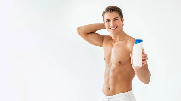 Schöner junger Mann mit Shampoo in der Hand — Stockfoto