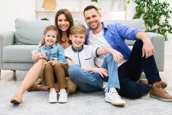 Прекрасна сім'я сидить на підлозі біля дивана позує вдома — стокове фото
