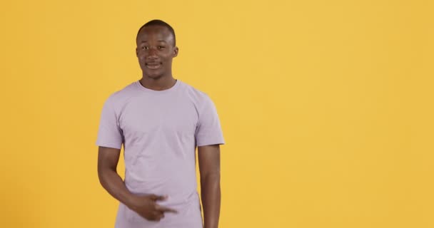 Fröhlich freundlicher schwarzer Kerl zeigt etwas und zeigt auf den Kopierraum — Stockvideo