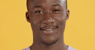 Kameraya gülümseyen mükemmel dişleri olan siyah bir adamın yakın portresi.