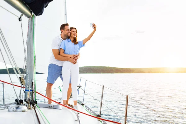 Casal lindo em pé no iate fazendo selfie durante o passeio de barco — Fotografia de Stock