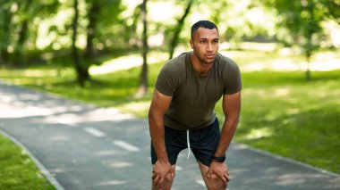 Yakışıklı Afrikalı Amerikalı koşucu yaz parkındaki sabah koşusu sırasında dinleniyor.