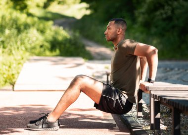 Parkın kaldırımlarında spor yapan siyahi bir adamın yan görüntüsü.