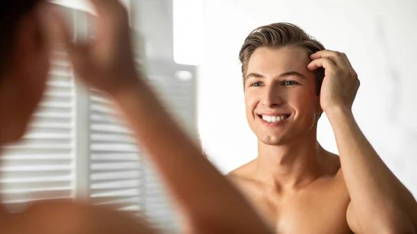 Joven guapo mirándose en el espejo y sonriendo — Foto de Stock