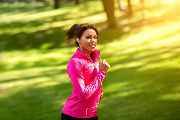 Chica bastante africana corriendo por el parque, escuchando música — Foto de Stock