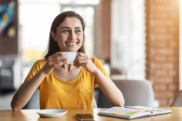 Radostná dívka pije kávu v kavárně, při pohledu na volné místo — Stock fotografie